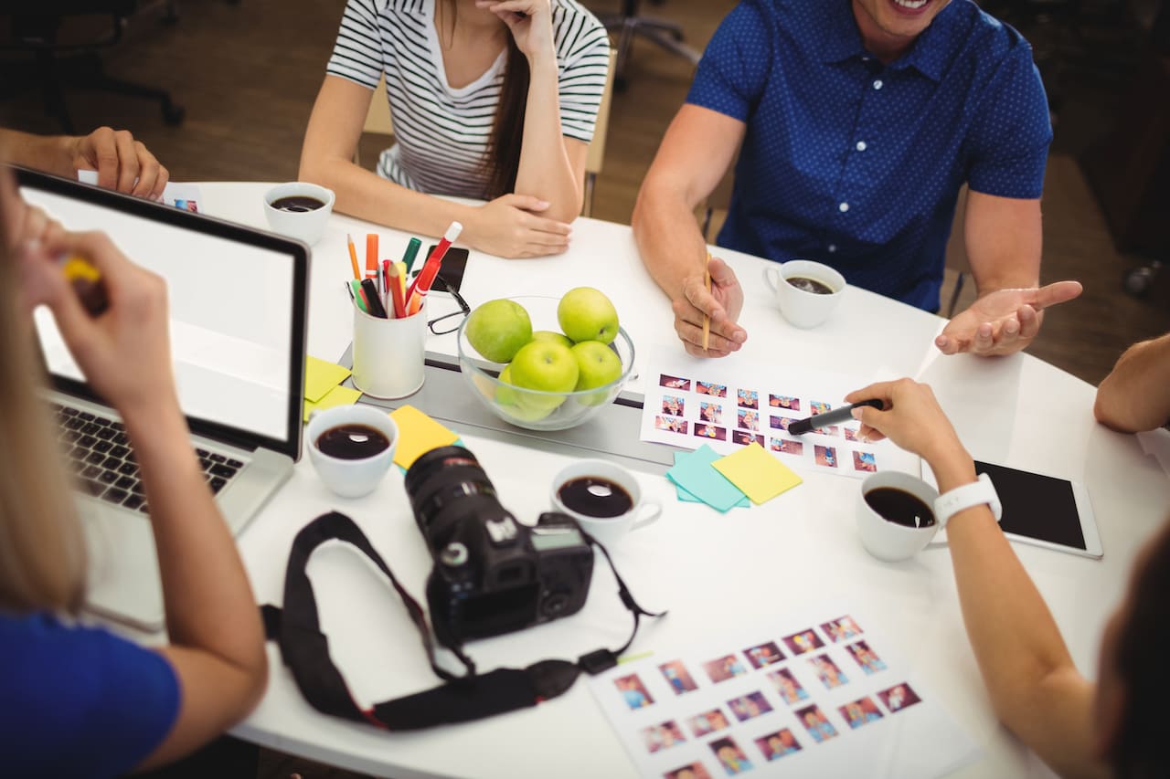 Graphistes en pleine discussion autour d'un bureau concernant un projet
