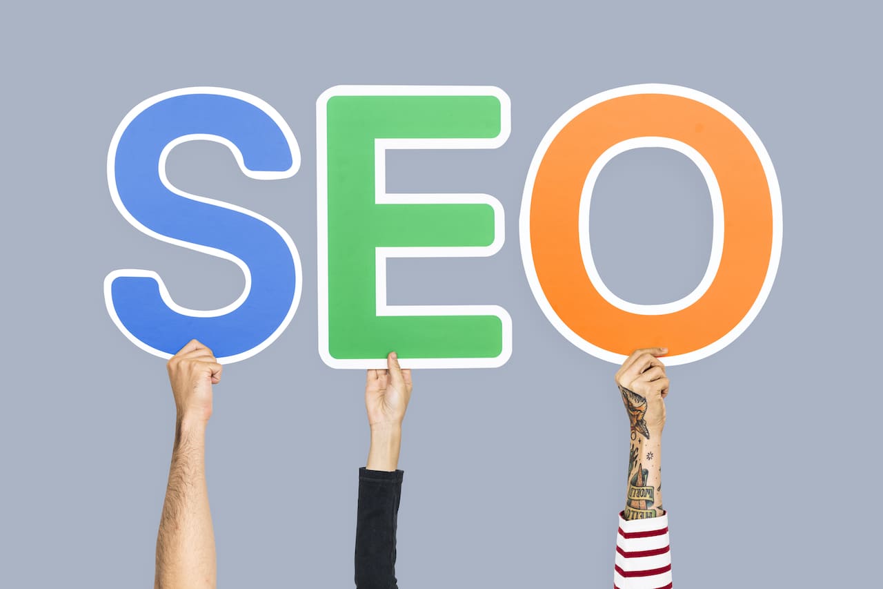 Mains tenant des lettres colorées formant l'abréviation SEO